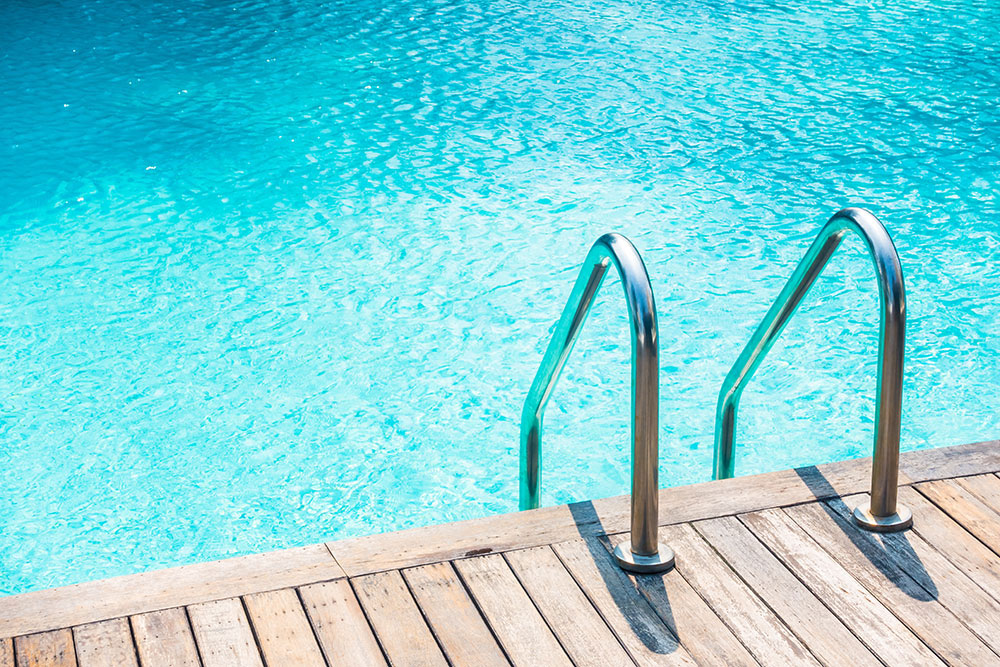Echelle inox accès piscine reflet bleu eau transparente