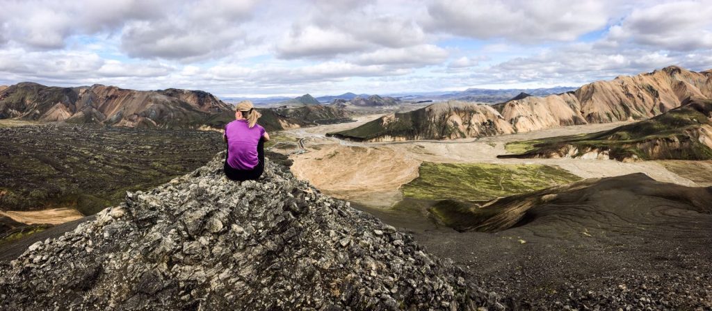 Paysage volcans Islande femme t-shirt violet blonde queue de cheval assise regardant au loin